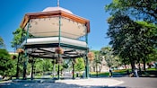 A Victorian bandstand as tall as the trees in its park, with hanging bouquets of flowers on each post