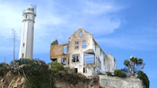 The Alcatraz Island Lighthouse stands next to the dilapidated remains of a building