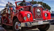 The front grill of a vintage fire engine has a chrome emblem of a skull