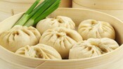 Cinco bollos dim sum en una vaporera de bambú