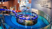 An elaborate museum features a mix of midcentury brownstone walls and glass walkways with displays