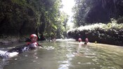 Pessoas com equipamento de segurança se divertem flutuando em um rio exuberante de costas
