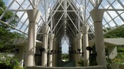 Concrete pillars in a row with triangular metal trusses supporting a roof in a forest setting