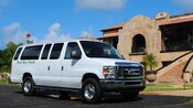 A large van with tinted windows sits in front of a Spanish style mansion