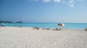 A quiet beach with empty chairs in front of calm water
