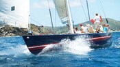 A sail boat filled with passengers cuts through the water