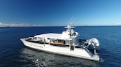 A catamaran floats in the ocean near 3 small islands