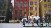 A young family of 4 eating ice cream and admiring the sights while sitting in a European town
