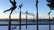 Statues of angels on pillars near chairs and an overlook of a city