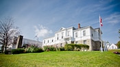 A building with windows, a chimney and a front lawn area featuring shrubs and flowers