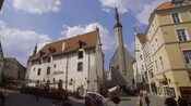 A busy restaurant with a sign written in calligraphy on a street corner with medieval buildings