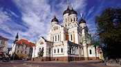 An ornate church with decoratively arched roof and towers topped by onion domes and orthodox crosses