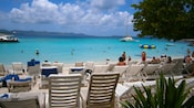 Guests relaxing in the water of a pristine shallow water lagoon lined with rows of beach chairs