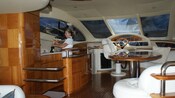 A crew member opens a bottle of wine next to the cockpit of a yacht