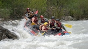 6 men in an inflatable raft floating down a white water river