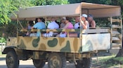 Pasajeros de un camión de safari al aire libre que recorren los terrenos de una granja de avestruces