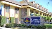 The front of Best Western Plus Raffles Inn & Suites accented with hedges and Agapanthus plants