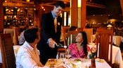 A server pours wine for a couple sitting at a dinner table at Napa Rose restaurant
