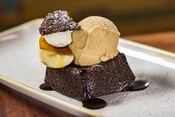 A plated brownie topped with ice cream, powdered sugar, chocolate sauce and more