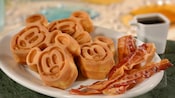 Fatias de bacon em um prato, com miniwaffles no formato do Mickey Mouse