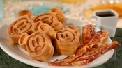 Slices of bacon on a plate with waffle bites that resemble Mickey Mouse