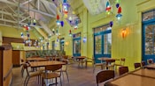 Área de comidas aireada y colorida con móviles coloridos que cuelgan de un techo alto en el restaurante The Artist's Palette