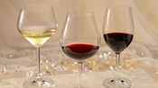 Una copa de vino blanco cerca de una copa de vino tinto cerca de una copa de pinot noir