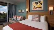 Un dormitorio con una cama, almohadas, un sofá, pinturas, una cortina decorativa y acceso al balcón