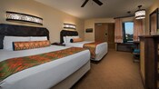 Dos camas Queen Size de estilo caribeño, asiento para equipaje/cama nido, mesa redonda y, detrás, una puerta y una ventana