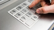 Gros plan sur les doigts d’un homme appuyant sur les touches d’un clavier d'un guichet automatique