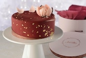 An Amorette’s Patisserie signature cake on a pedestal next to its hat box packaging