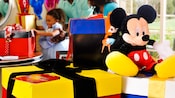 Coloridas cajas de regalo envueltas con un gran Mickey Mouse de peluche sentado encima
