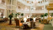 Áreas con butacas con respaldo, sillones y muebles de mimbre en el interior del vestíbulo de Disney's Grand Floridian Resort & Spa