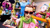 Mannequins in a retail store displaying sunglasses, scarves, necklaces and T-shirts
