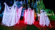 Translucent ghosts on a lawn of the Haunted Mansion after dark