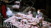 Ghoulish dinner party scene with 3 ghosts sitting at a dinner table at the Haunted Mansion attraction