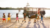 7 niños y una mujer disfrazados de piratas marchando en la playa