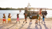Uma mulher e 7 crianças vestidas de pirata andam em uma praia