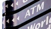 Placas direcionais que lembram um filme, uma com setas e as letras "ATM"