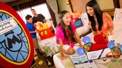 Una joven familia está muy entusiasmada por encontrar obsequios y sorpresas de Disney esperándolos en su habitación de hotel