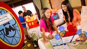 Une jeune famille est ravie de trouver les cadeaux et les surprises Disney qui les attendent dans leur chambre d'hôtel