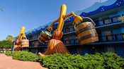 2 versiones gigantes de las escobas bailarinas con baldes en las manos de Fantasía de Disney adornan el costado de Disney's All-Star Movies Resort