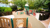 A sandy playground with a climbing apparatus, slide, nets and monkey bars