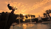 Silhueta contra o pôr do sol da Sorcerer Mickey Fountain na Fantasia Pool no Disney’s All-Star Movies Resort