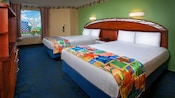 Dos camas dobles con una sola cabecera curvada de madera que abarca ambas camas
