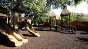 A gravel playground with slides and platforms under thatched roofs at Disney's Animal Kingdom Lodge