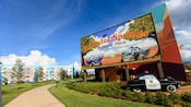 Une voiture de shérif sous un panneau d’affichage indiquant en anglais : « Radiator Springs, une ville où il fait bon vivre »