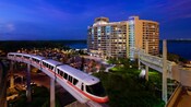 The monorail in motion, passing by Bay Lake Tower in the evening
