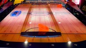 View of an air hockey table with 2 orange paddles