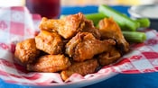 A pile of buffalo wings on a plate with celery sticks